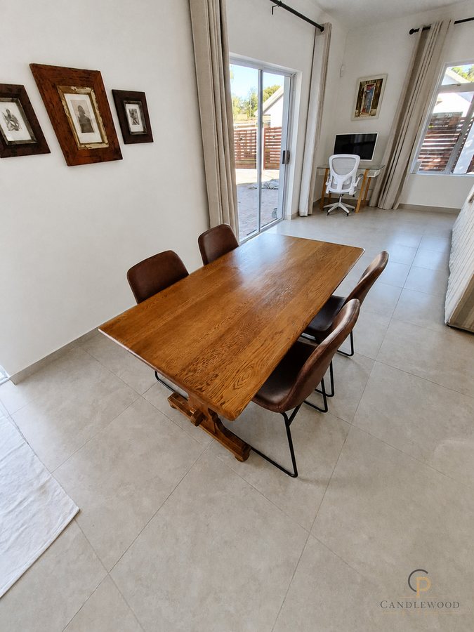 Solid wood dining table seating four, beside the garden doors